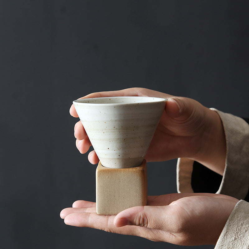 A white Stone Base Espresso Cup on its base held in two hands