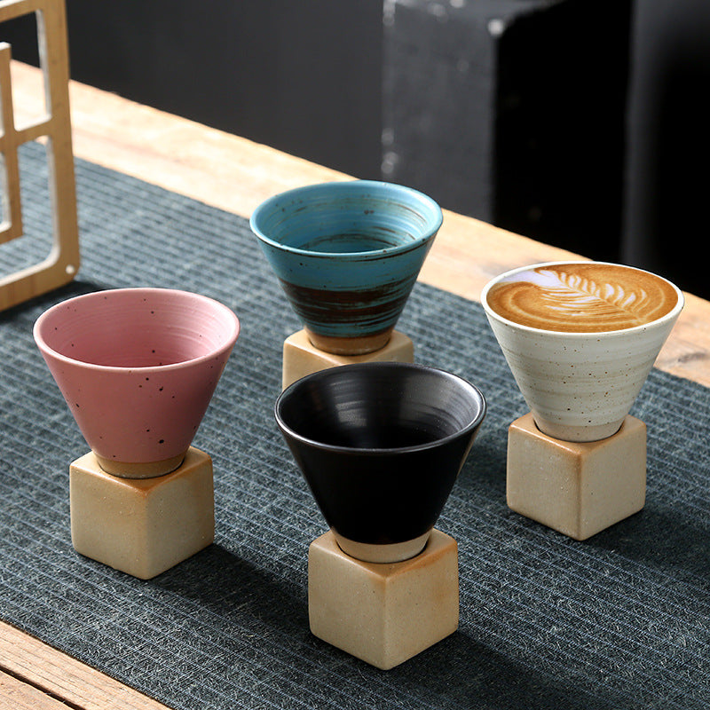 Stone Base Espresso Cup in four colours, each seated on its cube base on a table runner