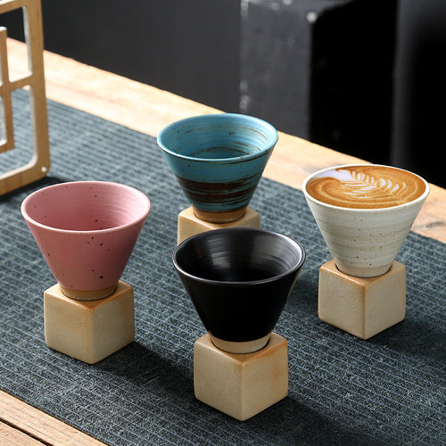 Stone Base Espresso Cup in four colours, each seated on its cube base on a table runner